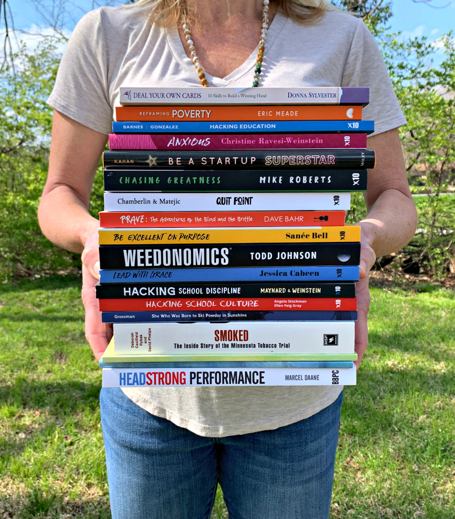 Photo of editor holding a stack of published books.