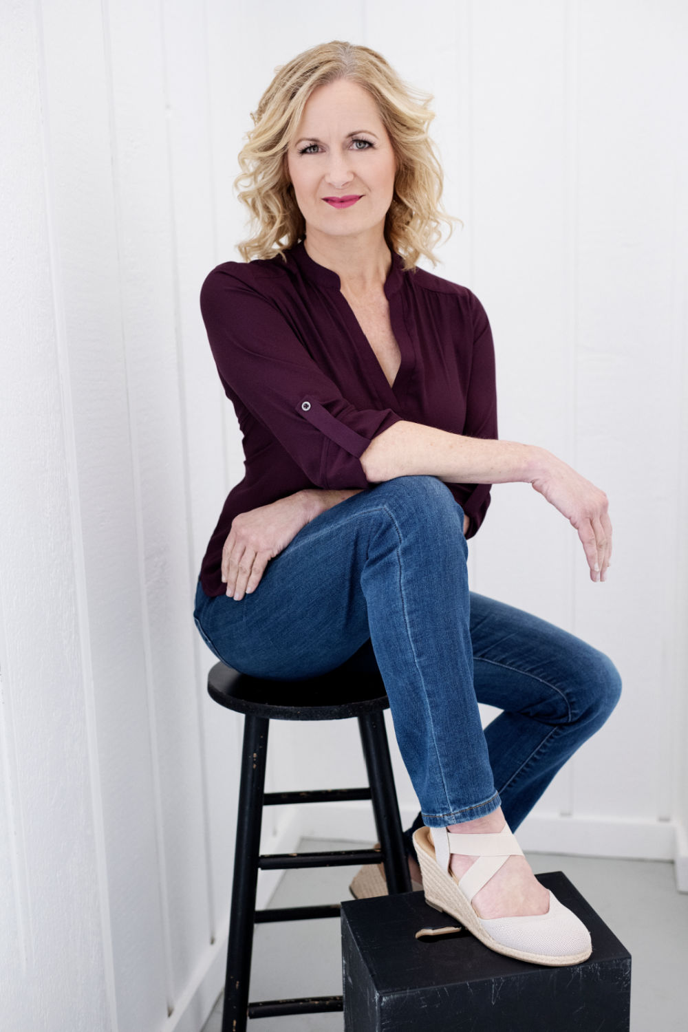 Jennifer sitting on a stool with one foot on a riser, smiling and relaxed